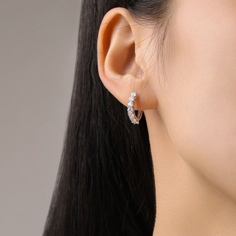 Photo of a woman wearing silver hoop earrings with diamonds
