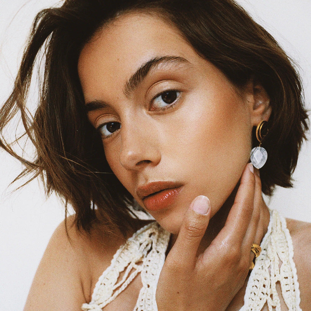 Photo of a woman wearing drop earrings in white and gold with pearl